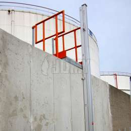 Secured access ladder for industrial installations Closed JOMY retractable ladder installed on a facility wall outside of a storage tank area.